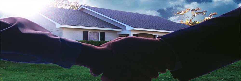 photo of hands shaking in front of a house